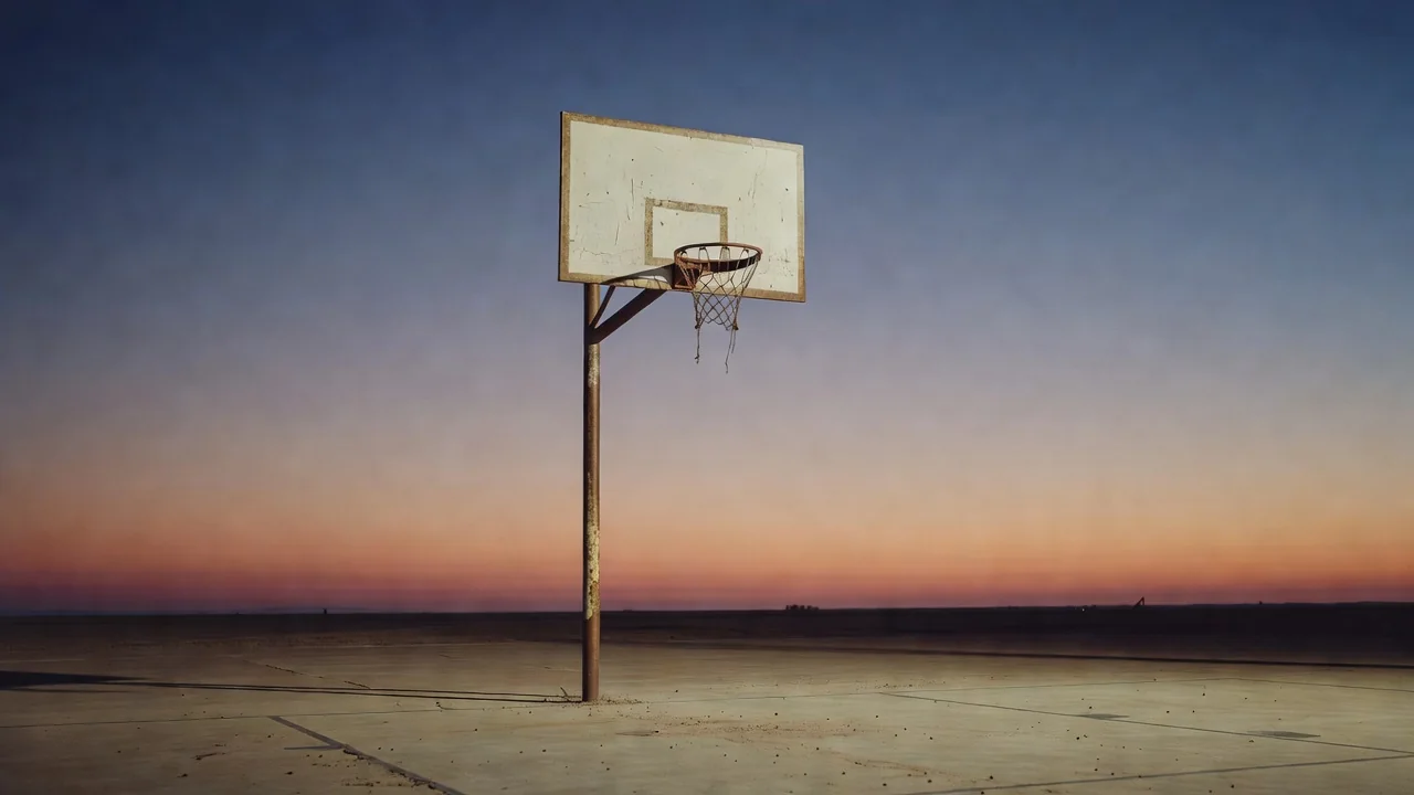 Basketball net and rim photographed outdoors against evening sky